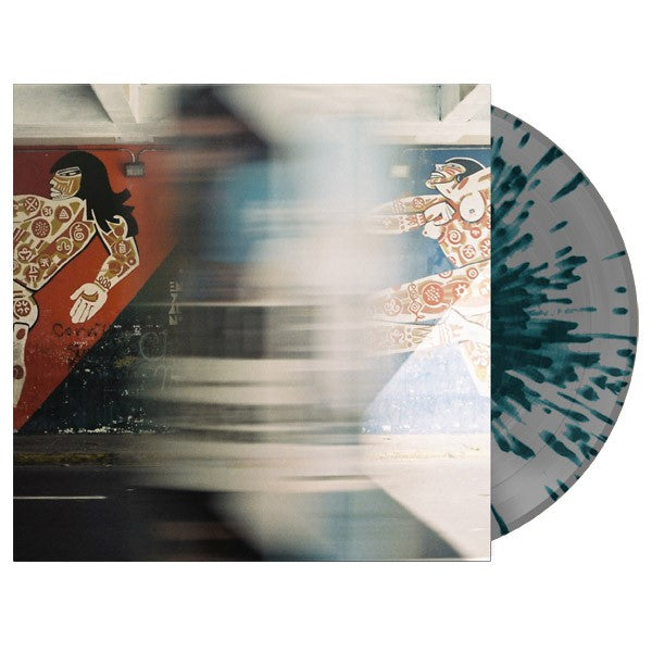 A Limited Edition Weathered vinyl with a gray and green splatter design partially slides out of an album cover showing a blurred street scene with two colorful murals of stylized people on the wall.