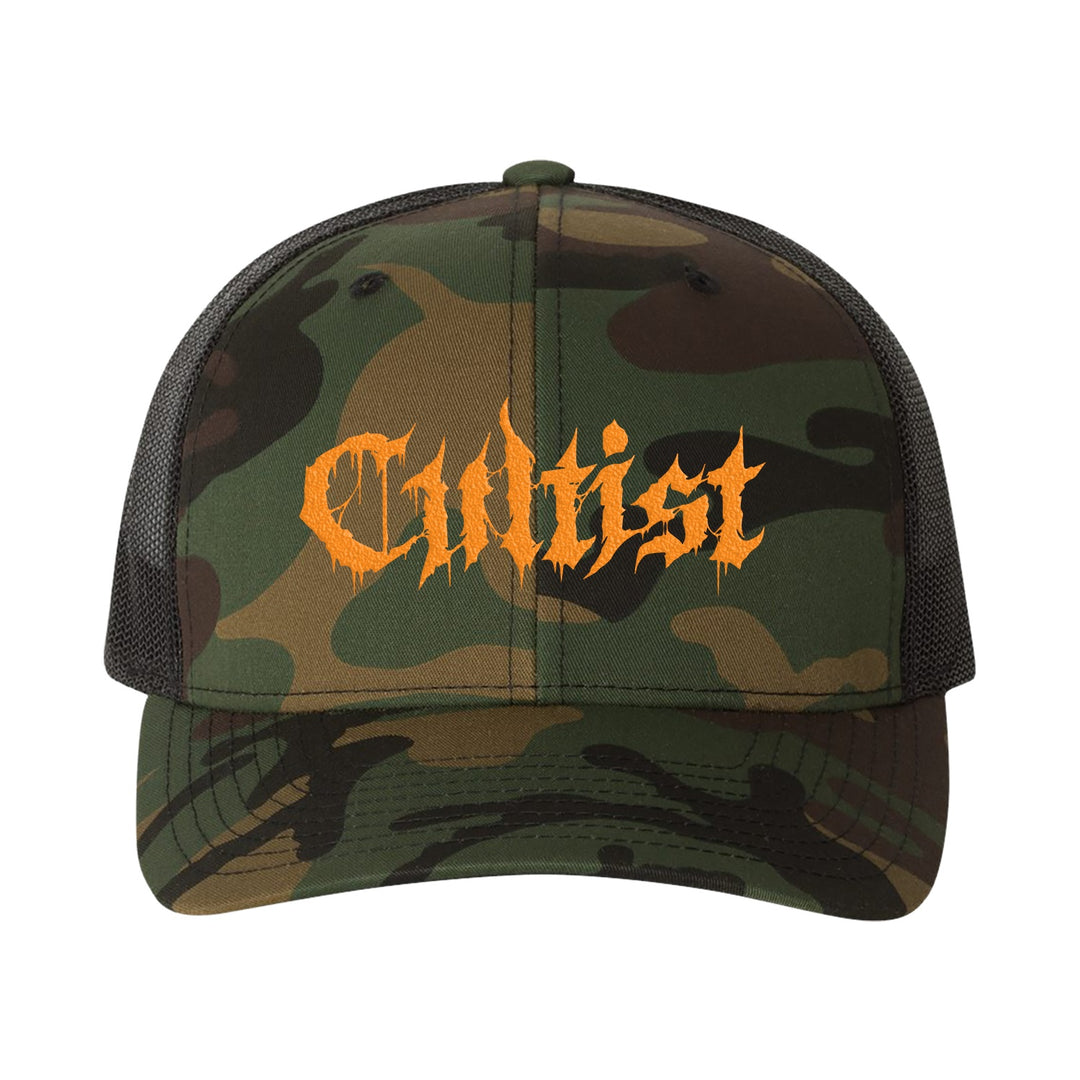 The Cultist camo trucker hat features black mesh sides and bold, jagged orange "Cultist" lettering across the front for a standout look.
