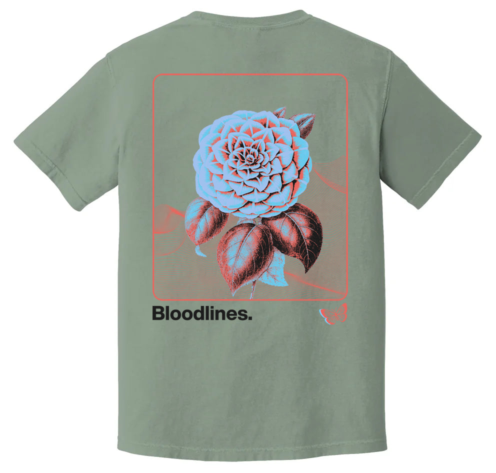This Bloodlines green Comfort Colors tee features a large blue and red rose with a red frame on the back, Bloodlines. in black at the bottom, and a small butterfly outline beside the text.